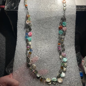 Längre dekorativt halsband  - Längre halsband i olika material, metall, snäckor mm. Inget att anmärka på.