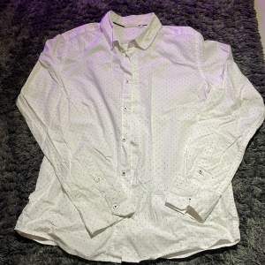 Skjorta från Kappahl i färgen vit med svarta prickar. Använd endast få gånger och är i ett mycket bra skick. Inga tecken på användning alls.