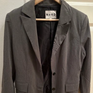 Grå na-kd blazer - Fint skick, köpt på Plick men ej blivit använd av mig så säljer vidare. Kan behöva en omgång med strykjärnet bara ;) den är storlek 36, men passar även 38. Önskas fler bilder hojta!