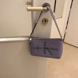 Calvin klein lila väska - Använder inte längre, i bra skick, har haft på mig 2 gånger, är bra väska om du ska ut.