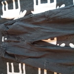 Cago Byxor - Svarta cargo byxor från hm. Slitna vid hälen och lite små sliten ficka (se bild 2 och 3). Sitter ner till ankeln på mig som är 168. 