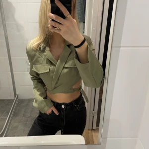 Blazer topp - Justerbara korsade spännen. Vaddering i axlarna. Fint skick.