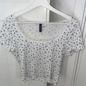Blommig topp - Blommig croptop från h&m med spetsdetaljer samt rosett framtill. Nyskick, aldrig använd.