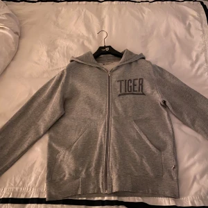 Tiger of Sweden zip-hoodie - Grå Zip hoodie från Tiger of Sweden med broder Tiger på vänstra bröstet. Bra skick, storlek Medium. Vid vidare funderingar är det bara att höra av sig!