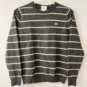 Grå Ylletröja från Lacoste - Grå ylletröja från Lacoste med vita vågräta ränder. Storleken är 3 (ca S) men den kan ha krymt lite så passar främst XS. 9/10 skick. Funderingar samt prisförslag välkomnas! LIKNANDE PLAGG PÅ PROFILEN