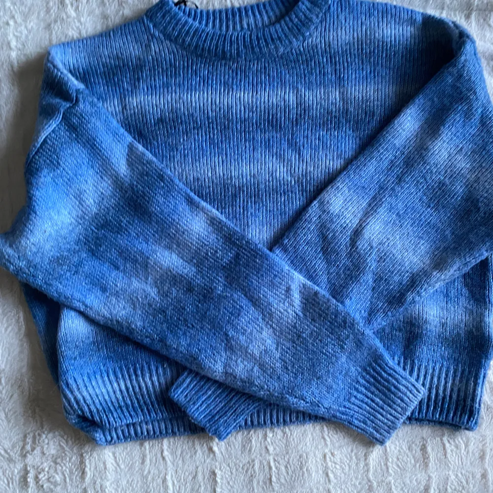 En stickad tröja med olika blå färger, lite kortare i modellen och den är inte så len som många stickade tröjor är. Har aldrig använt den. Bra skick!. Stickat.