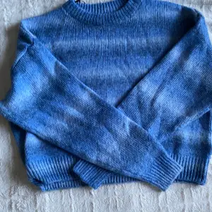 En stickad tröja med olika blå färger, lite kortare i modellen och den är inte så len som många stickade tröjor är. Har aldrig använt den. Bra skick!