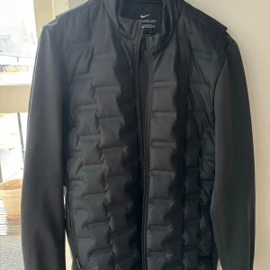 Golfjacka aeroloft Nike dun  - Svart Golfjacka från Nike med dunvaddering över bröst och halva ryggen. Ingen anmärkning, sparsamt använd. Strl S. Perfekt som vårjacka på golfbanan då den stoppar vind på vadderad yta.  Inköpt för 2500:- 
