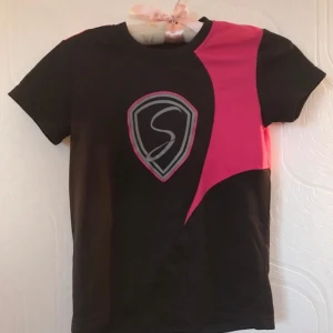 Fin sport T-shirt  - Svart T-shirt med rosa inslag som är perfekt för till exempel idrott eller träning. Från märket Skill i storleken 134/140. Super bra skick.