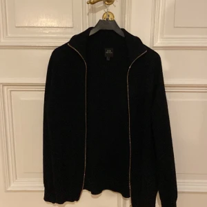 Svart Zip Up - En stickad svart Zip Up från Armani-Exchange. Ny skick! Storlek S men sitter som M. Ny pris ca 1300kr.