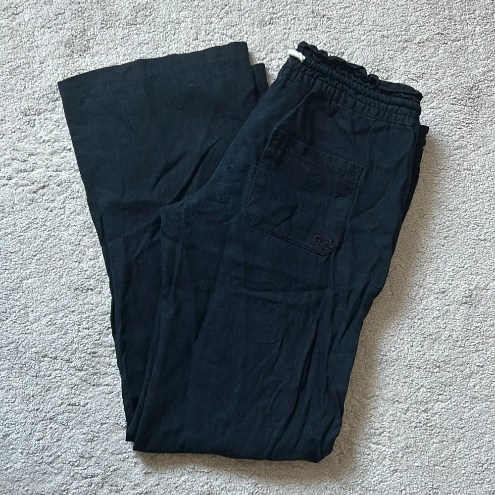 Svarta linnebyxor från Roxy i storlek XS. Dom är i mycket bra skick förutom ett litet hål bak på byxan, se bild.. Jeans & Byxor.