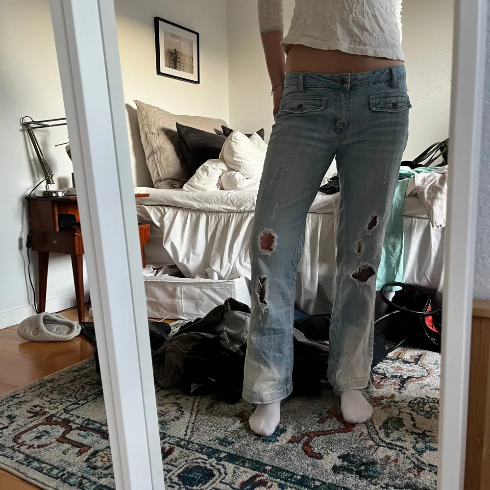 Lågmidjade bootcut jeans med hål på bak och framsida. Så coola detaljer, passar S💕. Jeans & Byxor.
