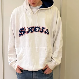Amerikansk hoodie - Denna vita hoodie från Haruwood classics är perfekt för alla som gillar mode och eller amerikansk basketboll! På framsidan av tröjan står det Sixters, vilket är ett basketlag i USA. Storleken är uppskattningsvis XL eller stor L. Bra kvalite.