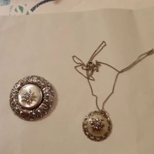 Kedja Silver 835 med hänge samt brosch . - Kedja i Silver 835 o hänge och brosch mönstrad i metall .stämpel på låset på kedjan .Fint skick .