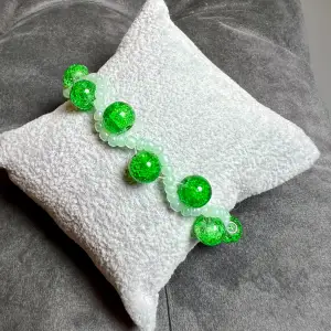 Egentillverkat vågigt pärlarmband i grönt, med krackelerade pärlor och silverfärgat spänne. Justerbar passform mellan 19-24 cm.