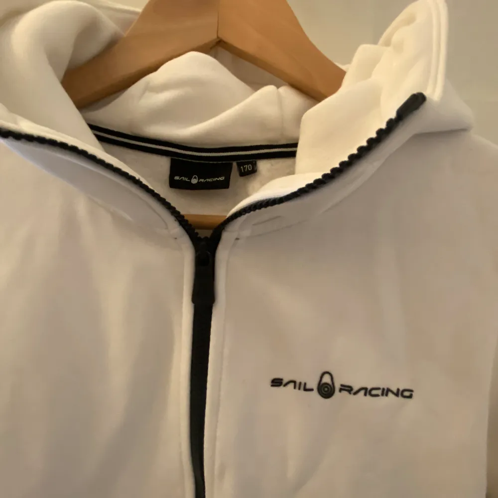 Säljer en vit zip hoodie i fint skick.  Färg: vit Märke: Sail Racing. Köparen står för frakten . Hoodies.