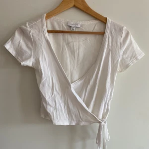 Söt topp - Vit ribbad topp från Topshop med omlott. Den är verkligen så fin och sitter superfint på, passar perfekt ihop med kjolar men också superfin ihop med jeans! Köpare står för frakten✨
