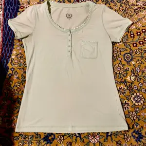 Jättesöt turkos t-shirt, perfekt till sommaren! Med knappar och en (riktig) ficka. Storlek M men passar även mindre