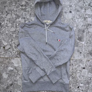 Maison Kitsuné Hoodie - Storlek xs grå maison Kitsuné Hoodie. Väldigt bra skick, inga defekter, säljer pga att hoodien är för liten