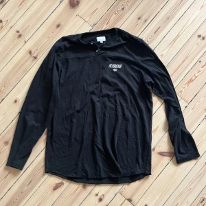 Svart långärmad tröja från Supreme - En svart långärmad tröja från Supreme. Tröjan har en enkel design med Supreme-logotypen tryckt på bröstet. Den är tillverkad i ett mjukt och bekvämt material.