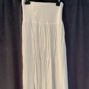 Lång kjol  - Lång kjol med smock i midjan. Hög slits i sidan. Aldrig använd. Storlek S. Säljer även en svart. Kolla gärna mina andra annonser :)