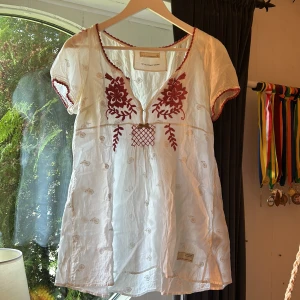 Odd Molly blus  - Säljer en fin odd molly blus som är lite längre i modellen. Den har mörk rosa och vita ditaljer på hela blusen. Storleken ligger mellan en S och en M 