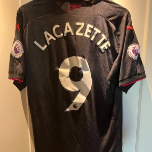 Arsenal tredjeställ 17/18 - Nyskick, i princip aldrig använd Alexandre lacazette 9 på ryggen med premier league logan tryckt på bägge armarna. Skick: 10/10 Går att diskutera fram ett bättre paketpris om det är intressant med någon mer av annonserna jag har ute!