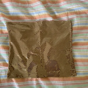 Guldkjol med paljetter - En glittrig guldtopp dekorerad med små paljetter. toppen har en tight passform och är kort i längden. Perfekt för festliga tillfällen.