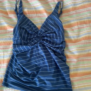 Blå randig bikini från Esprit - En blå randig badlinne från Esprit med justerbara axelband och en knutdetalj framtill. Linnet har en omlott-design och är fodrad på insidan.