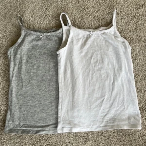 2 linnen - 2 linnen för 20kr  1 linne för 15kr 2 stycken linnen i vit och grå med en  liten rosett, st 122-128 men passar upp till 136-140