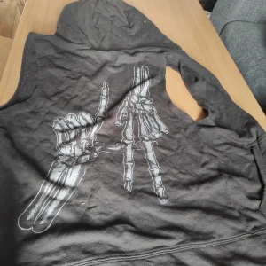 Zipphuddie - Grå zipphuddie utan armar. Tryck på baksidan. Sval och skön. Storlek S  (Det råkade hamna en trådbit på den på första bilden men den tillhör inte plagget såklart)