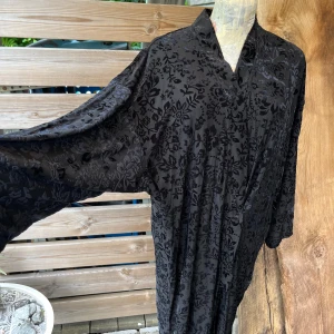 Så fin lång kofta/kimono med sammetsmönster  - Vacker lång kofta i kimono modell, vackert sammetsmönster i svart, snygg till det mesta. I fint skick stl M/L Är helt svart, har fotat i dagsljus så detaljerna syns ordentligt 