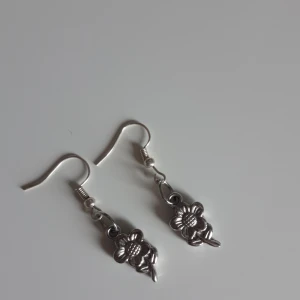 Örhängen  - Dom här örhägena har har gjort själv då det inte har något märke jag tycker att dom inte passar mig så därför säjer jag dom. Det är blommor i silver. 