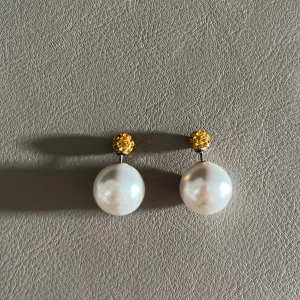 Pärlörhängen - Pärlörhängen där pärlan sitter bakom örat och den guldiga strass delen sitter på framsidan av örat. Aldrig använt.
