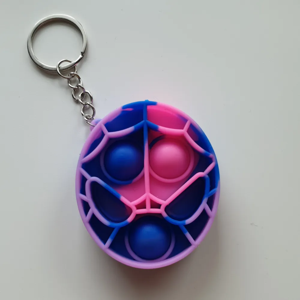 Pop-it/fidget toys nyckelring Färg: lila, rosa, blå  Form: spindelmannen huvud  Skick: oanvända. Ej lämpliga för barn under 3år. Då det innehåller smådelar. Accessoarer.