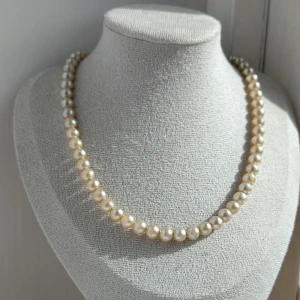 Pärlhalsband - Ett elegant pärlhalsband med vita pärlor. Halsbandet har en klassisk design med runda pärlor och en enkel låsning.i fint begagnat skick 