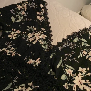 Sommarklänning  - En fin blommig klänning med spets i midjan och vid brösten. Det är en dragkedja bak på klänningen som går halvvägs sedan ska man knyta en rosett med band som går över ryggen