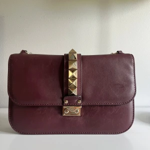 Valentino Garavani - glam lock Lether crossbody bag - Använt sparsamt. Färg: bordeaux/vinröd med guldiga detaljer. Inget slitage på kedjan.