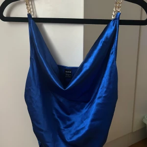 Shein blå topp storlek M - En blå topp med guldkedjor. Toppen har en djup urringning och en lös passform. Den är perfekt för en festlig kväll eller en utekväll. Aldrig använd helt ny utan prislappen kvar.
