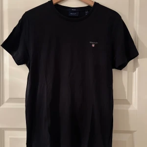 GANT Shield T-shirt Svart i strl. XS - Kortärmad tröja/ tee från Gant. Mycket fint skick! Svart i strl. XS.