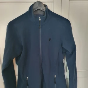 Tunn fleecejacka från Peak strl M - Tunn blå fleecejacka i stl M från Peak. Bra begagnat skick. Kommer från rökfritt hem med katt. Hämtas eller skickas om köparen betalar frakten.