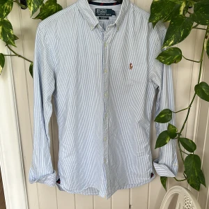 Randig Polo Ralph Lauren skjorta - En randig Polo Ralph Lauren skjorta. Skjortan är blårandig och har inga defekter. Den är i storlek M(slim fit). Nypris ligger runt 1700 kr. Kan gå ner något i pris vid snabb affär! Skriv vid funderingar😃