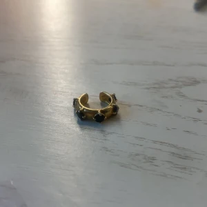 Ear cuff från maria nilsdotter -  Byter denna fina guldiga ear cuff med svarta stenar på för något slivrigt från maria. Köpte den för 1500kr och byter  för ungefär samma pris, har använt några få gånger. Köpte den för ungefär ett halv år sedan men är fortfarande i jätte skick.