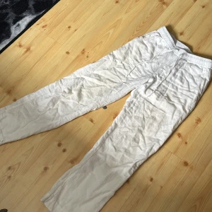 Vita linnebyxor från Neo Noir - Ett par vita linnebyxor från Neo Noir med elastisk midja och dragsko. Byxorna har en avslappnad passform och är tillverkade i ett lätt och luftigt material, perfekt för varma dagar.