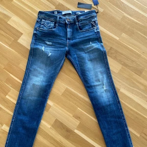 Blå jeansbyxor från Replay - Ett par blå jeansbyxor från Replay i modellen Anbass. Storlek 31W / 32L. Byxorna har en klassisk femficksdesign med slitna detaljer aldrig använda. Säljer då dem inte passade. Hör av er om frågor.