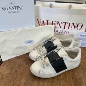 Valentino Garavani open sneakers - Ett par vita Valentino Garavani open sneakers. Skorna har en klassisk design med en låg profil och är tillverkade i skinn. ⚠️Allt i bilden ingår⚠️
