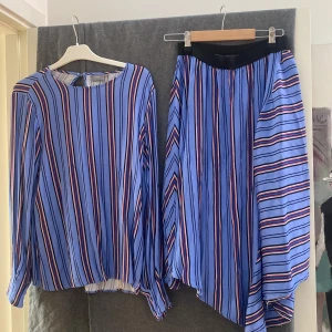 Matchande blus o kjol - Ett sätt i blått:  kjol  med resår i midjan och blusen har en liten puffärm. Material 100 viscose. 