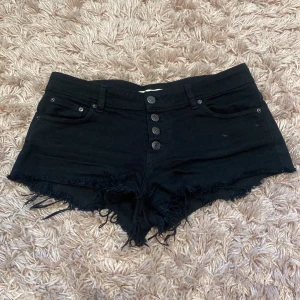 Lågmidjade jeansshorts  - Säljer dessa skit snygga jeansshorts som e lågmdjade med många knappar. Dem är svarta i storlek 38/M. De är i bra skick och kommer från Gina. Skriv för mer frågor💖🫶