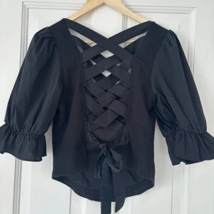 Fin svart blus - Mycket bra skick, passar bra i storleken, öppen i ryggen med jättefin snörning 