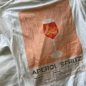 Vit t-shirt med Aperol spritz tryck posta ryggen.  Tröjan är köpt från några killars UF företag i Göteborg. Storlek S, men skulle säga att den mer sitter som en M i storlek💗 Endast provad. T-shirten passar för både tjejer & killar.